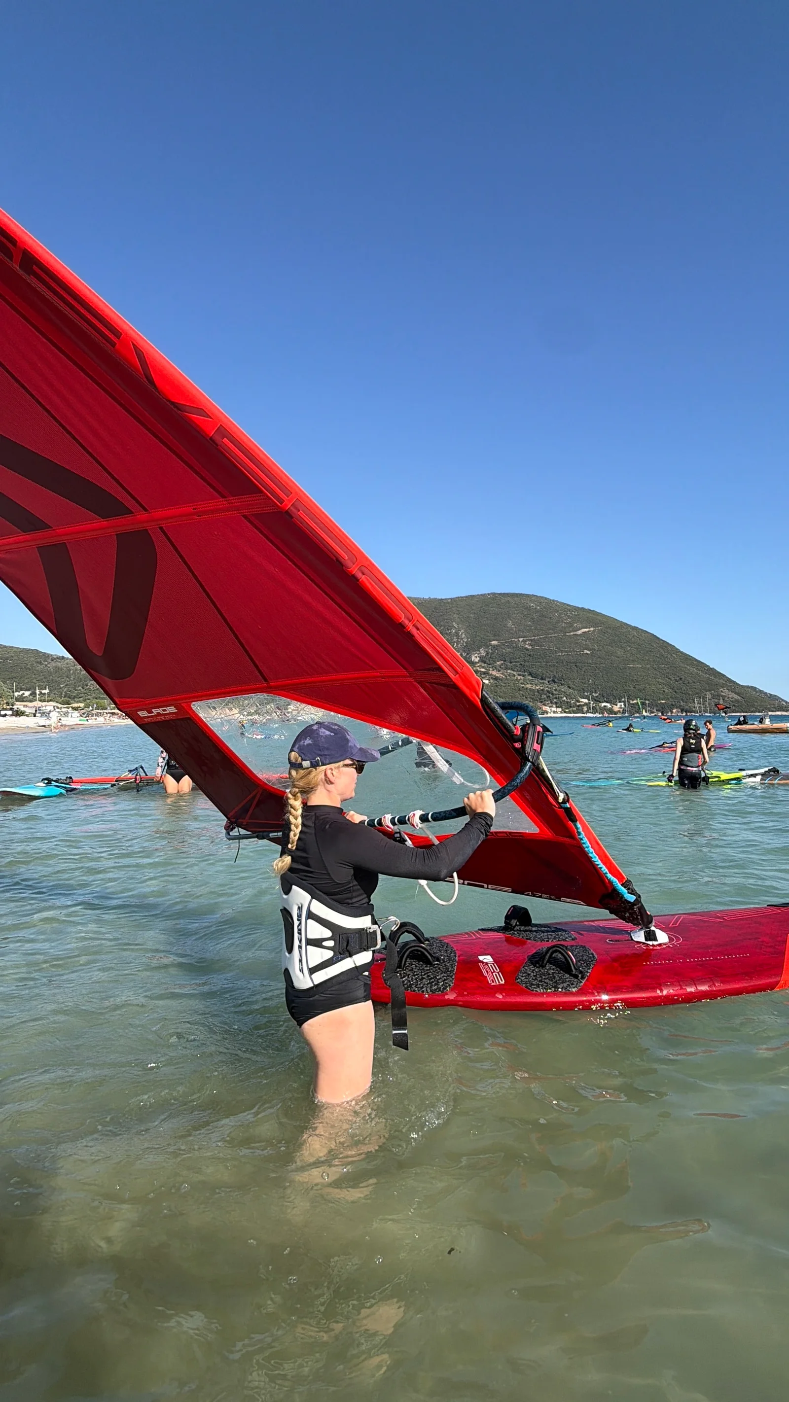 Uczestniczka z czerwonym żaglem windsurfingowym nad zatoką